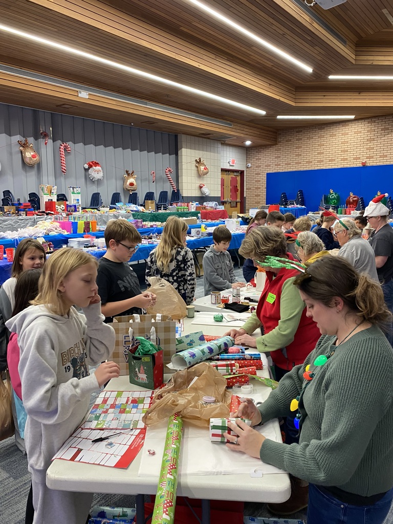 students at Jingle bell lane having adults wrap their gifts