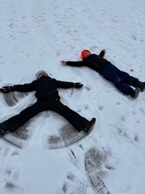 two students laying in the snow making snow angels