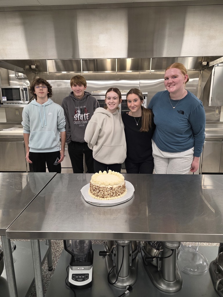 A mix of 5 female and male student in culinary class posing behind their butter pecan cake they made