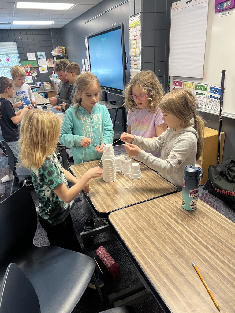 4 female 3rd graders unstacking a stack of styrofoam cups with only a string in order to build a christmas tree