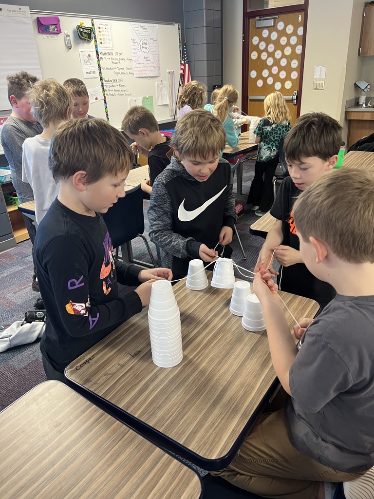 4 males students working together a desk to unstack cups with a string to build a christmas tree