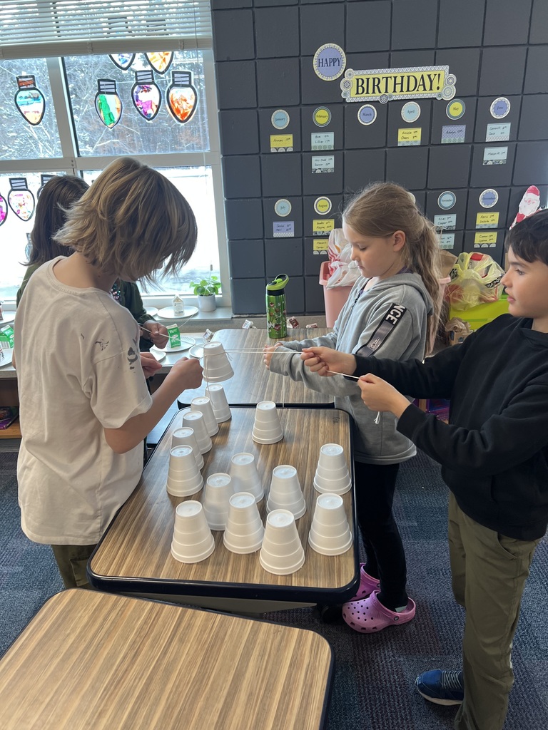 third grade students working together at their desks building a Christmas tree with styrofoam cups using only string