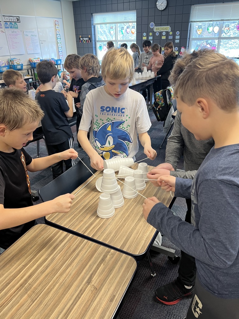 group of male 3rd graders working together to build a christmas tree using cups and string