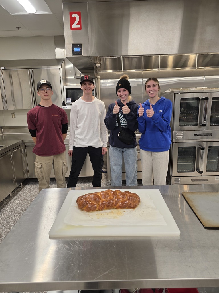 two males and two females who are giving thumbs up for their loaf of Challah bread that they made