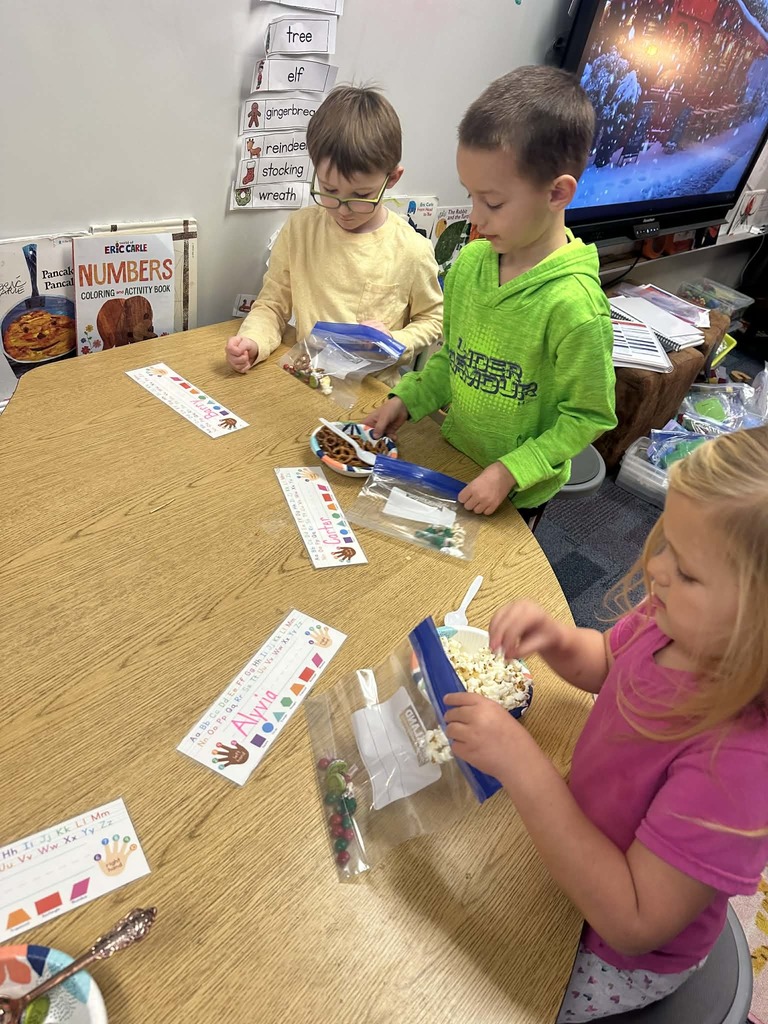 two male kindergarteners using pretzels and other food items in a baggie to make a snack