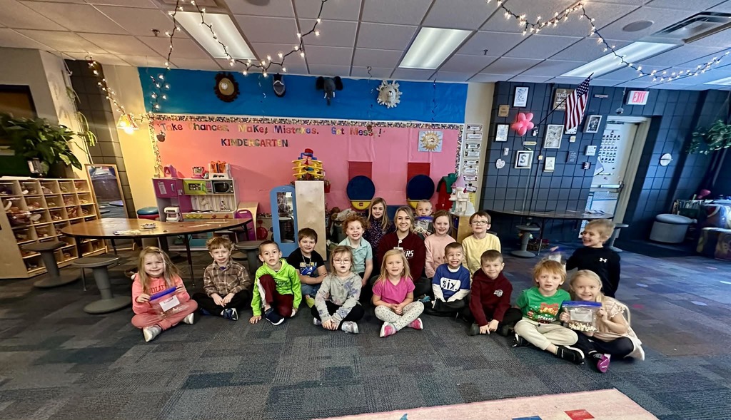 Kindergarten students sitting on the floow posting with goodies and the dietician from CRMC