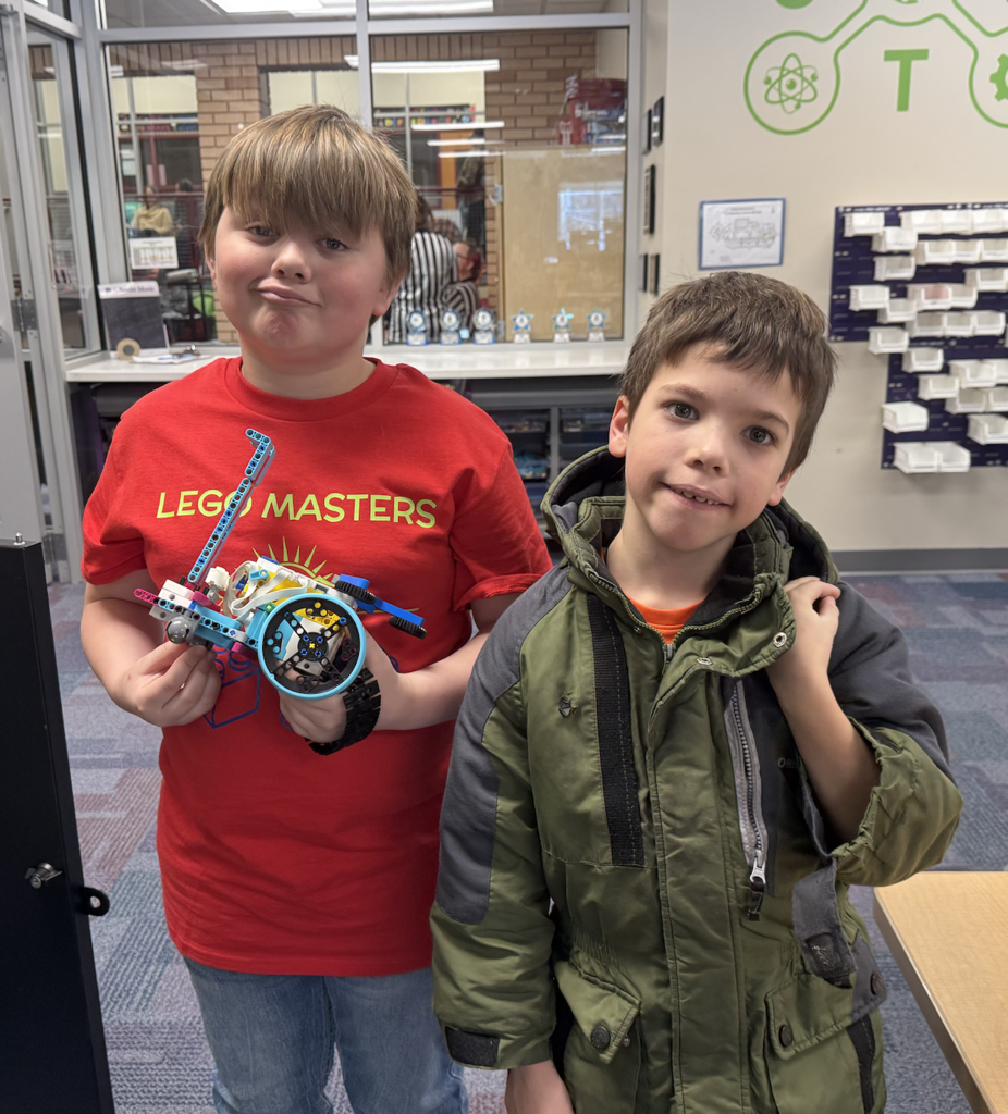 two male lego members one with a Lego Masters shirt on holding their lego creation