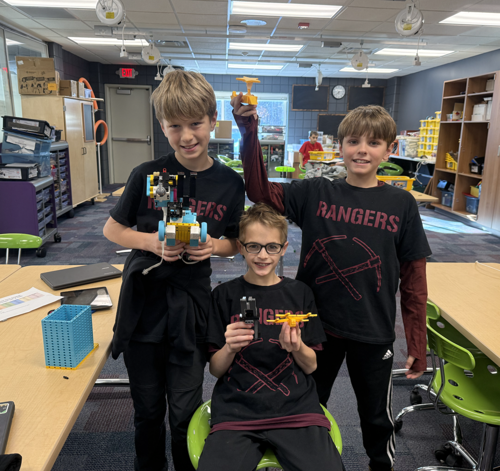 three male lego league team members holding their lego creations with Rangers shirts on
