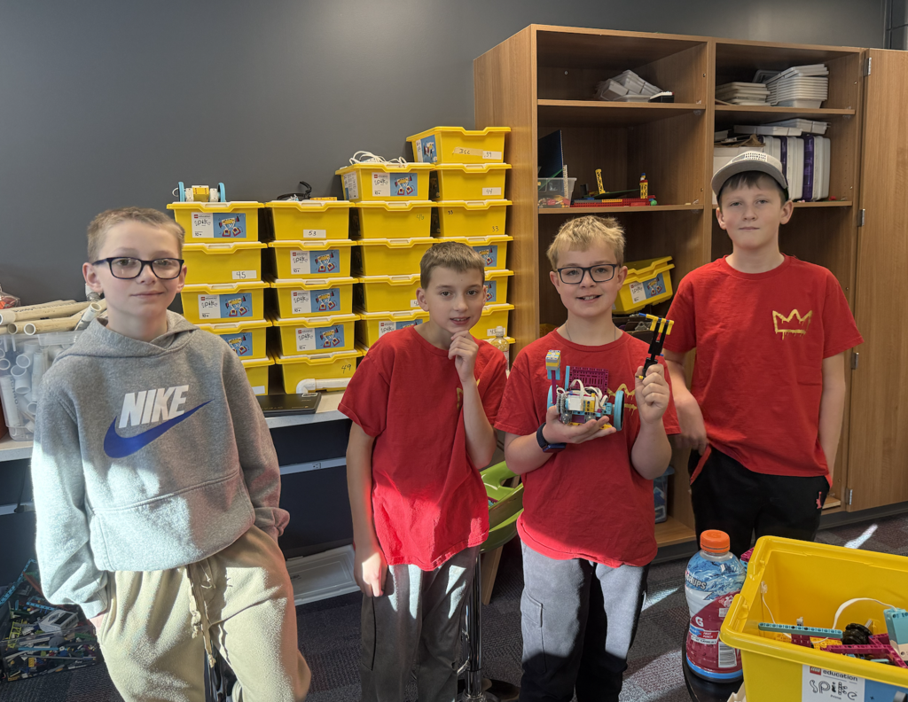 4 male lego team members in red shirts holding their lego creations