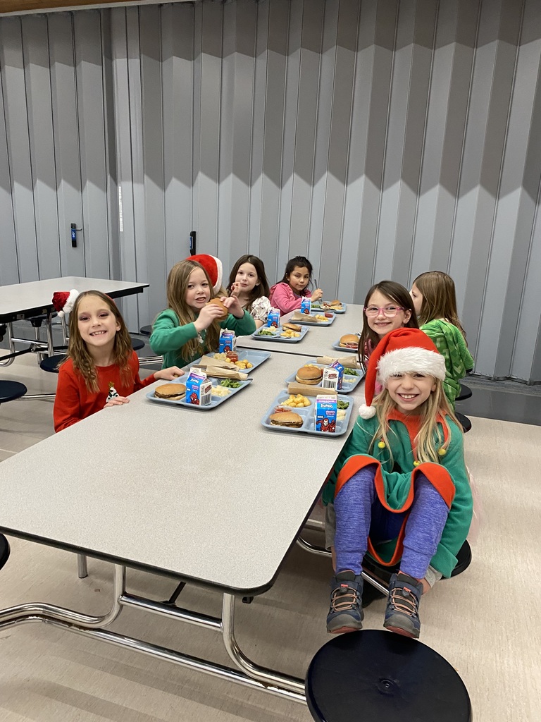 7 female students sitting at the lunch table eating lunch dressed for the holidays