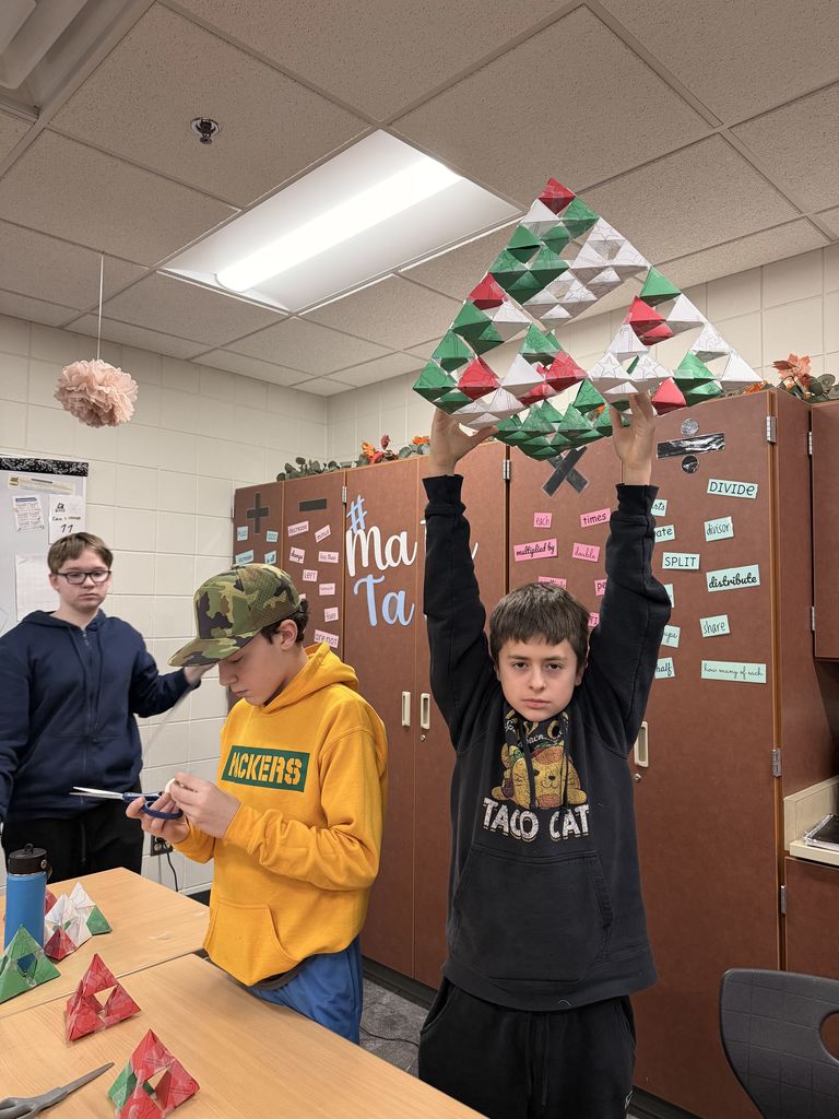 Male student holding up a bunch of Serpinksi triangles that created a Christmas tree