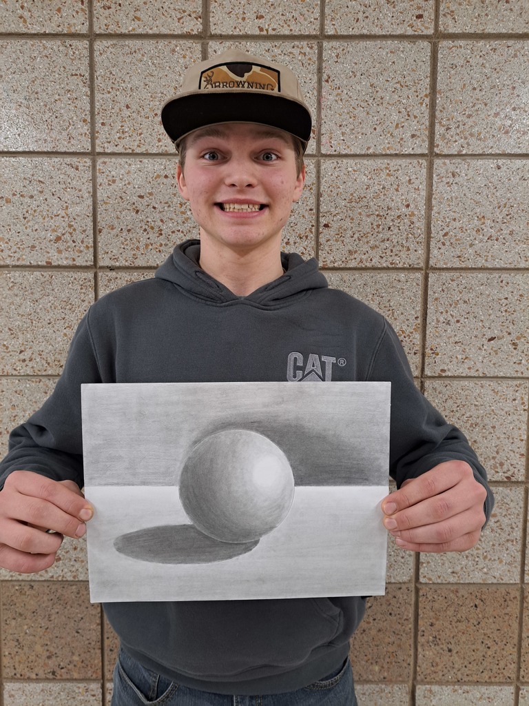 Male 8th grade student holding his drawing a 3d sphere drawn and shaded in pencil