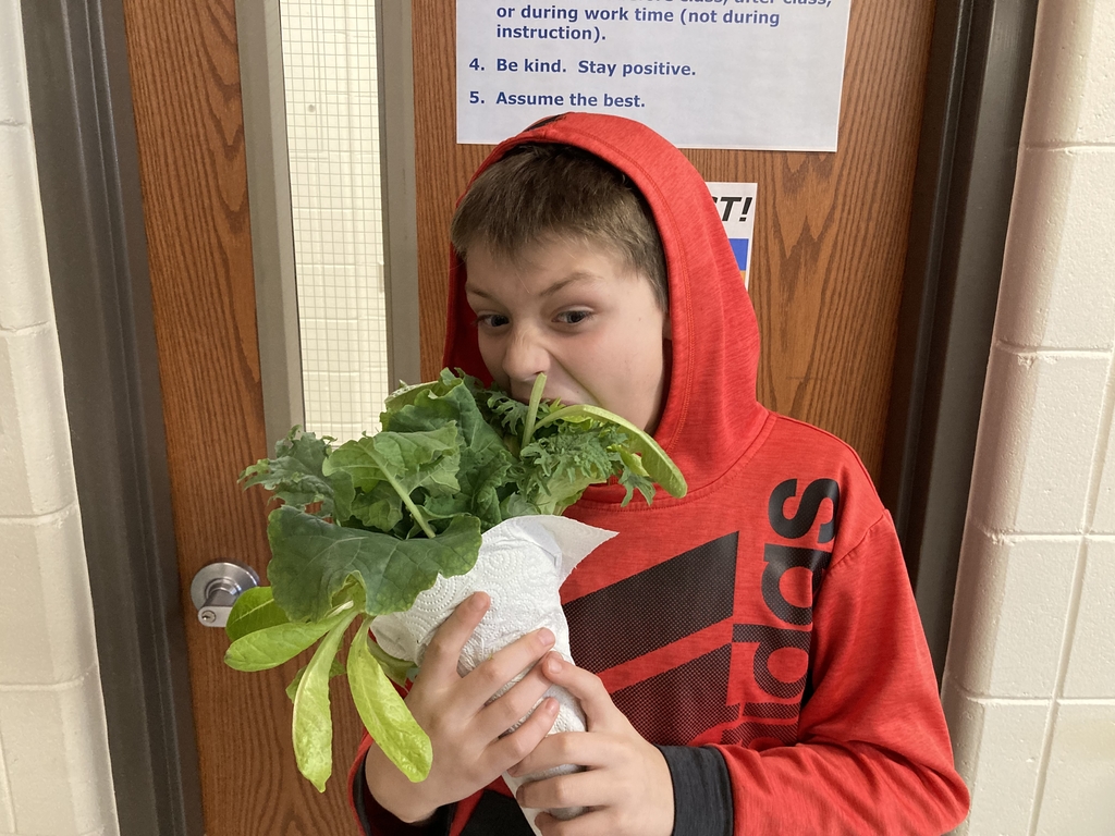student taking a big bite out of the lettuce that was grown in life science