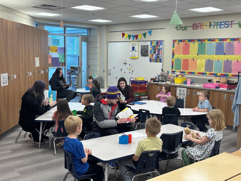 high school students sitting at separate tables reading to CRES  preschool students Dr. Suess books