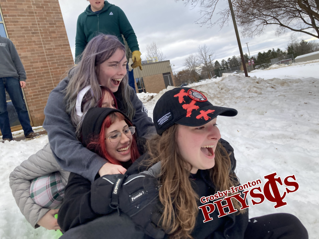 4 female students all piled on one sled going sledding at physics class
