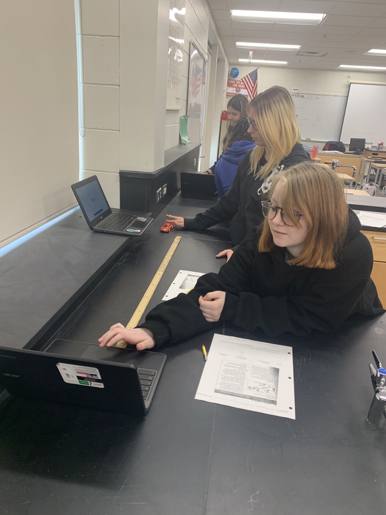 a student using her computer and a ruler to measure the speed of a wind-up car