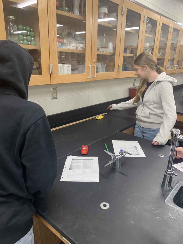 a female student letting go of a yellow wide up car so she can measure the speed
