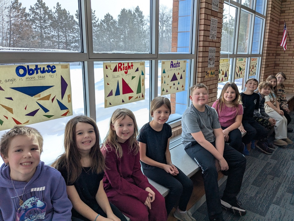 3rd graders sitting in the windows in the CRES media center underneath their posters of 6 different triangles an ways to reconize each of them