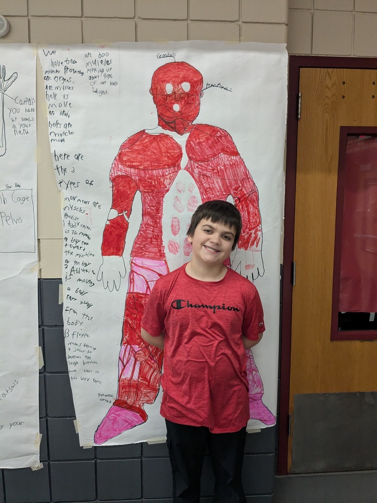 a male student standing in front of his drawing of the muscular system