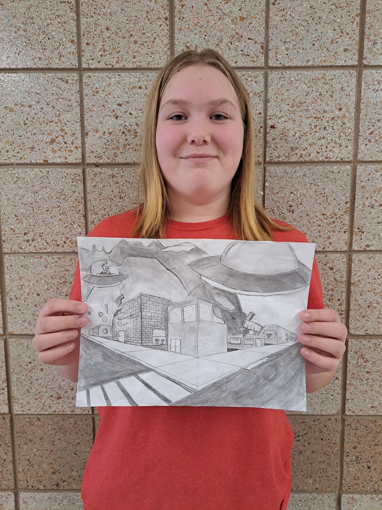 Student holding a 2 point perspective drawing of a city