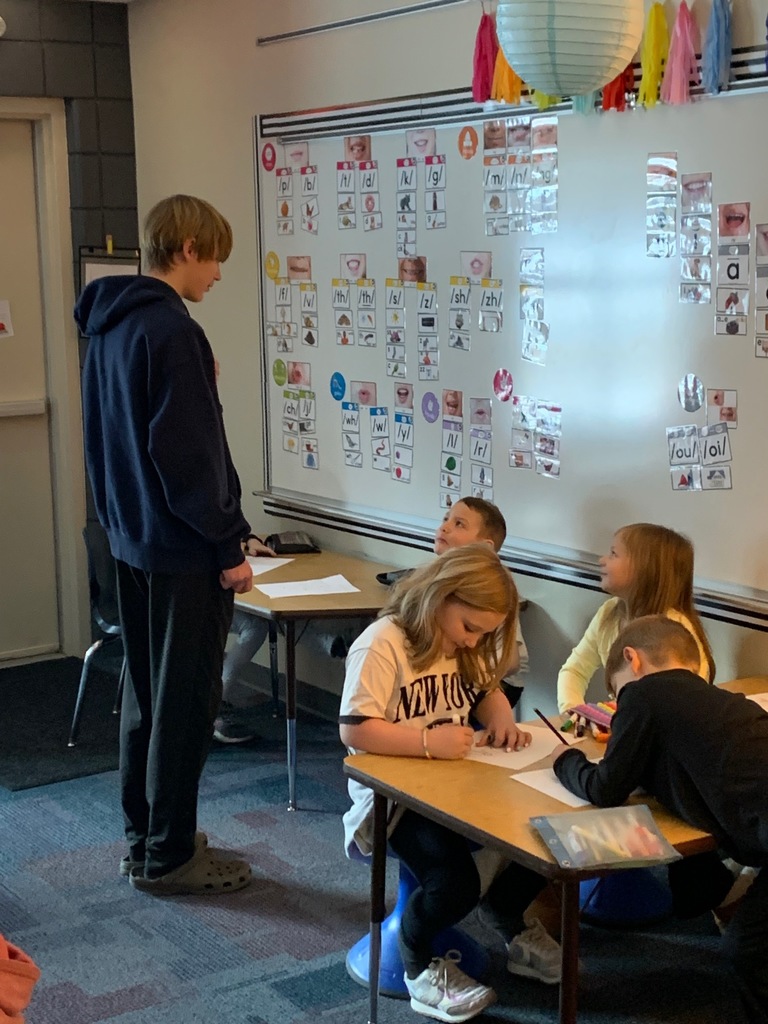 hs male student standing and talking to students sitting in their desks