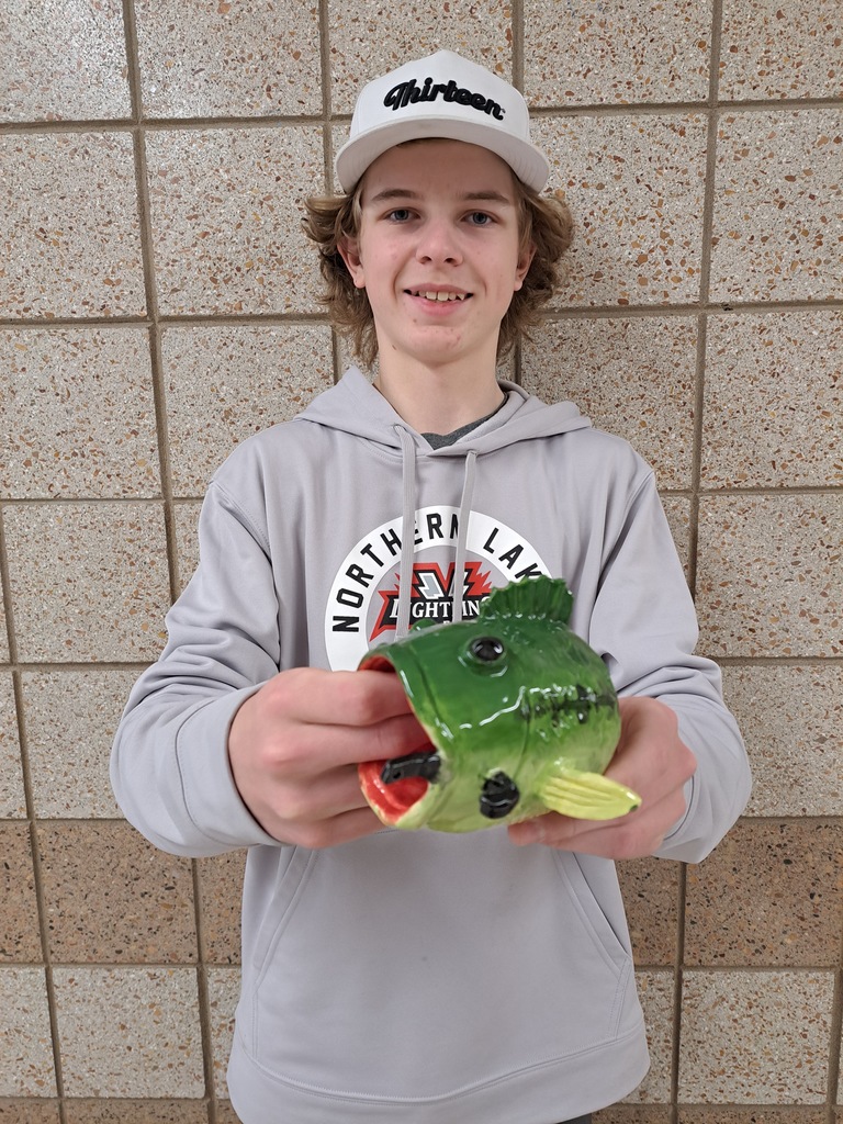 Male student holding a pinch pot of a bass that he made in art class