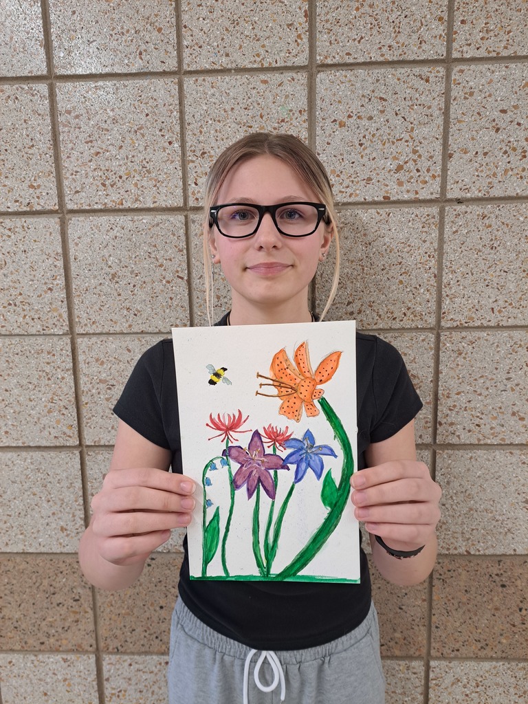 female student holding a drawing and coloriign of flowers