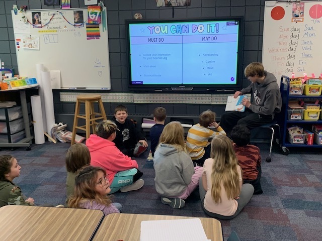 male children's literature student reading a book to CRES students during read across america week