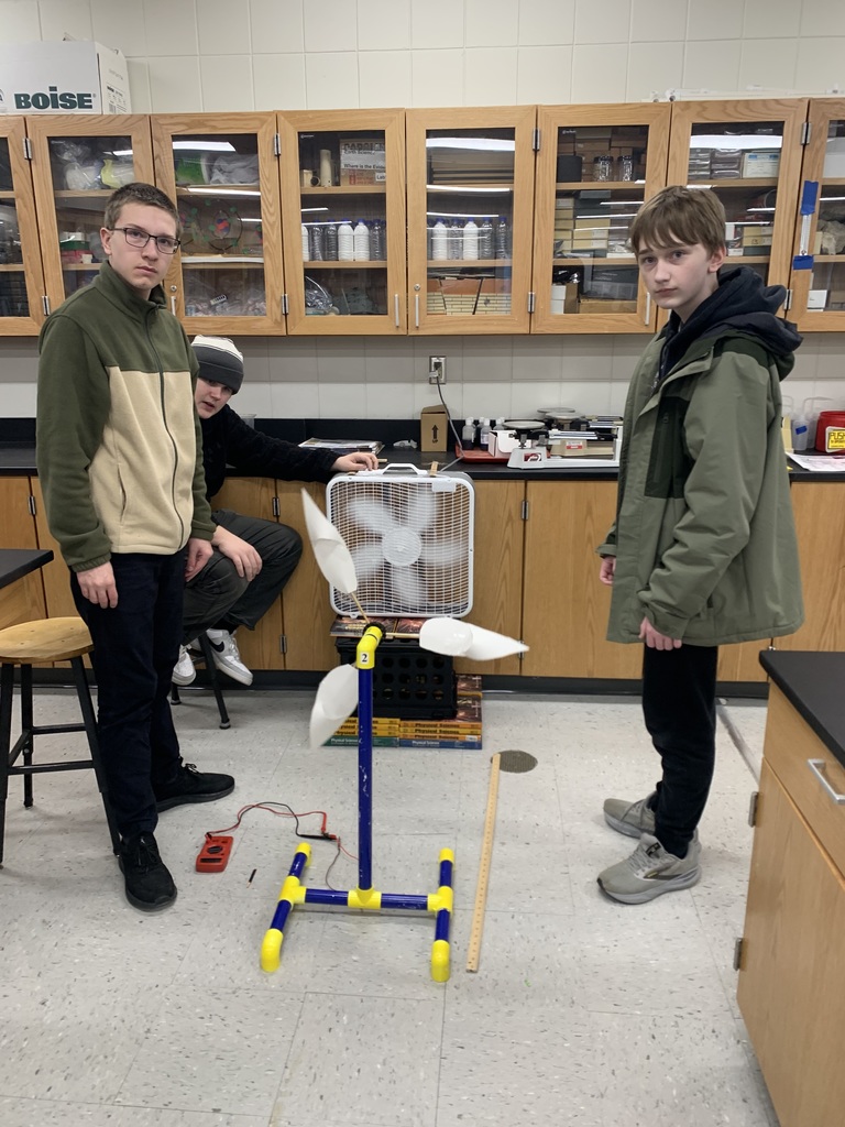 three male students near their make shift wind turbine with a big box fan