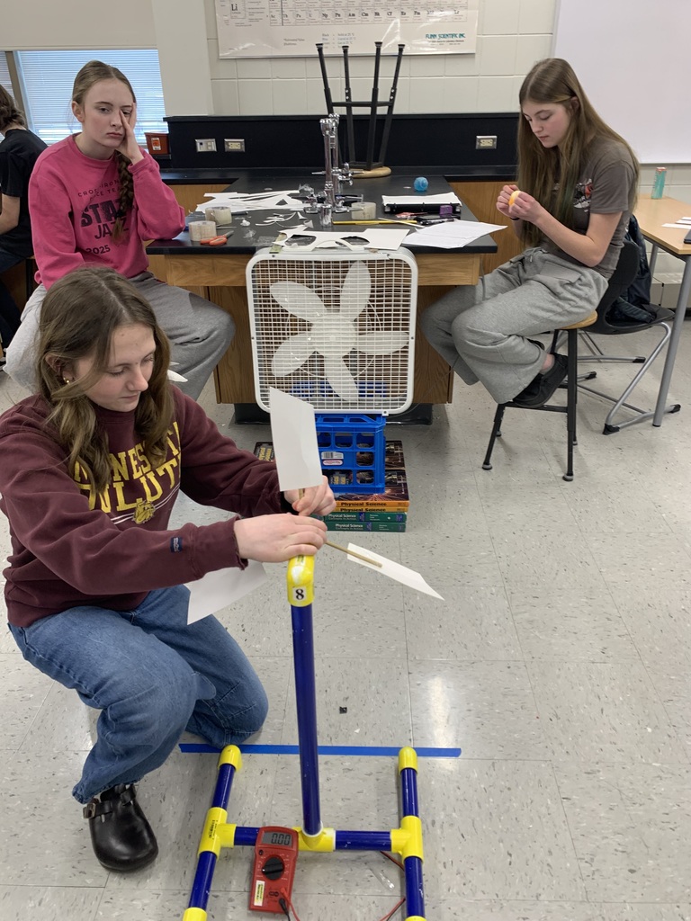 female student putting together the groups wind turbine while the two other two watch