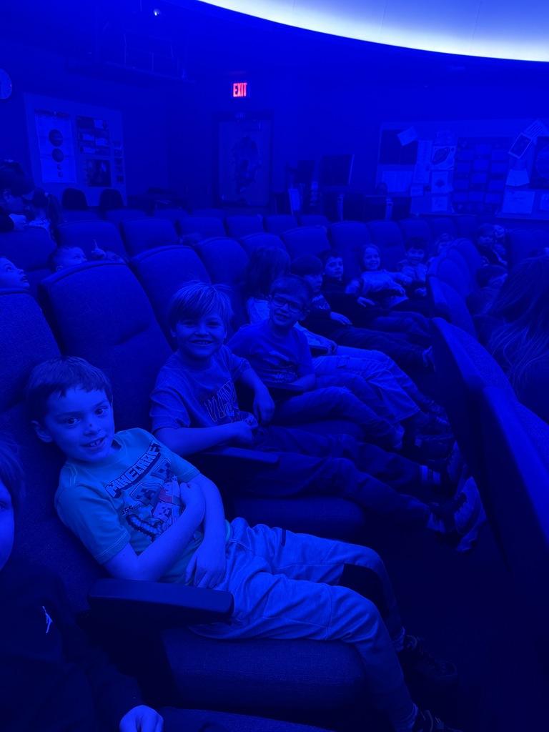first graders sitting in the seats at the planetarium