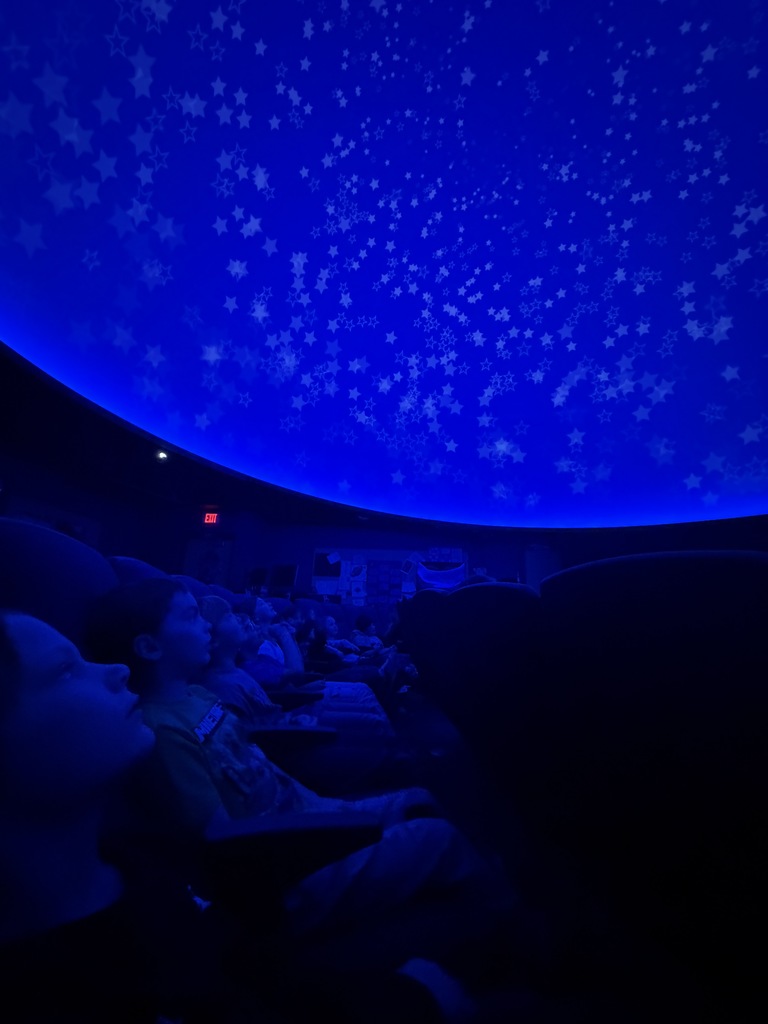 first graders sitting in the planetarium looking at the "sky"