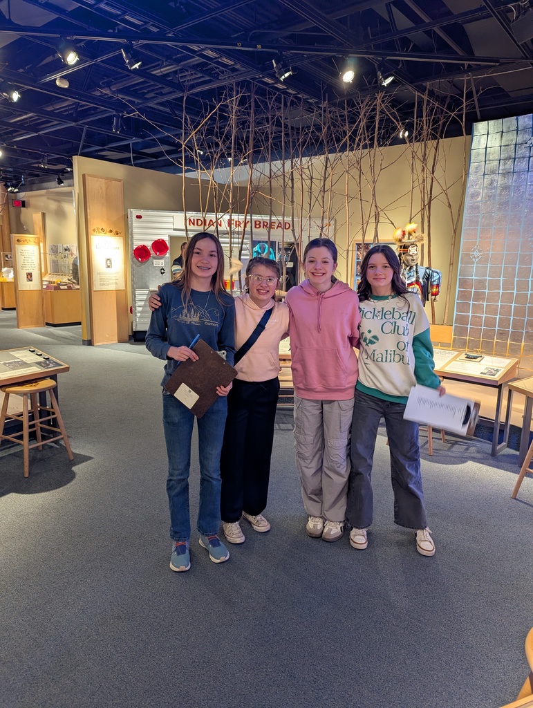 4th 8th grade females walking around the museum with clipboards