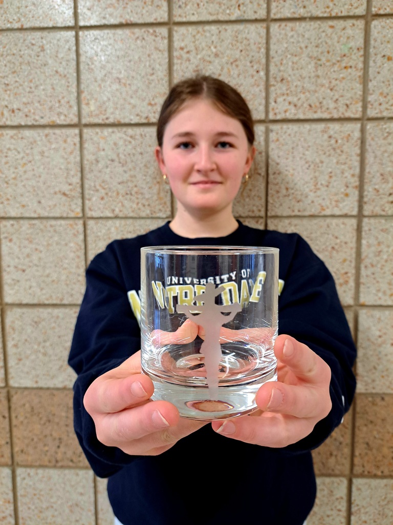 female student holding an etched glass that she made with an outline of Jesus