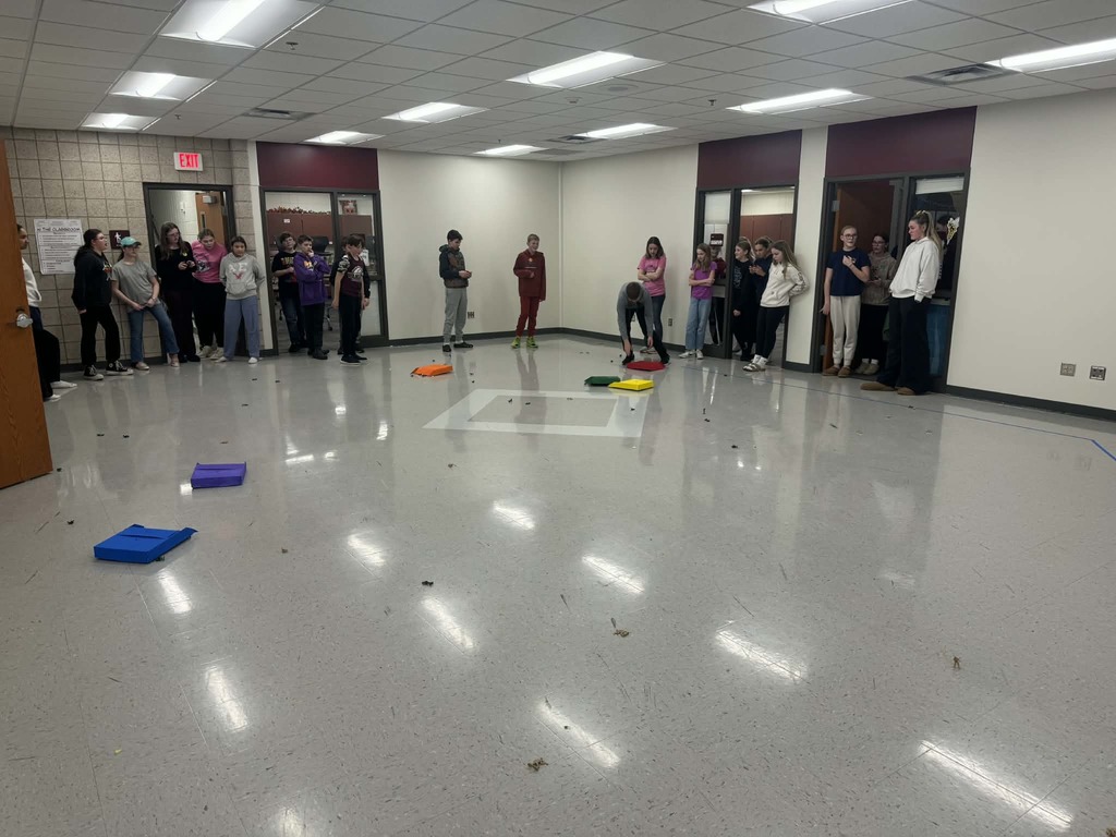 7th grade students and link crew leaders standing around an open area with little soldier figurines all on the ground