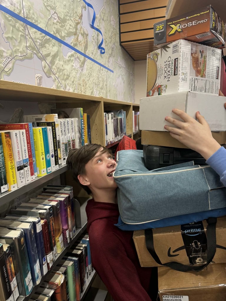7th grade student holding a stack of boxes and suitcases at Link Crews event Shanaboom
