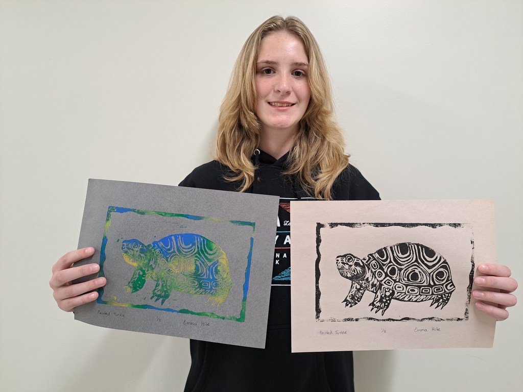female holding a colored print and a black and white print