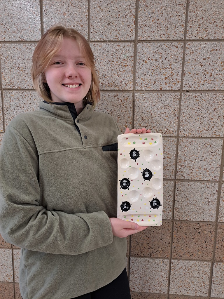 female student holding a mancala board  that she made 