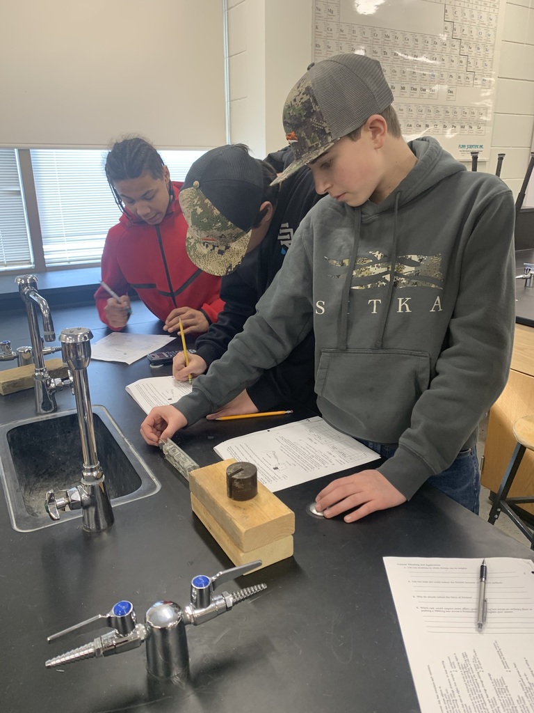 three male students writing on their worksheets about friction