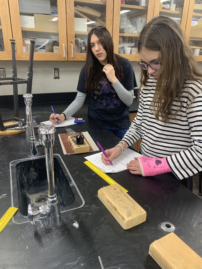 two female students writing on their papers about friction