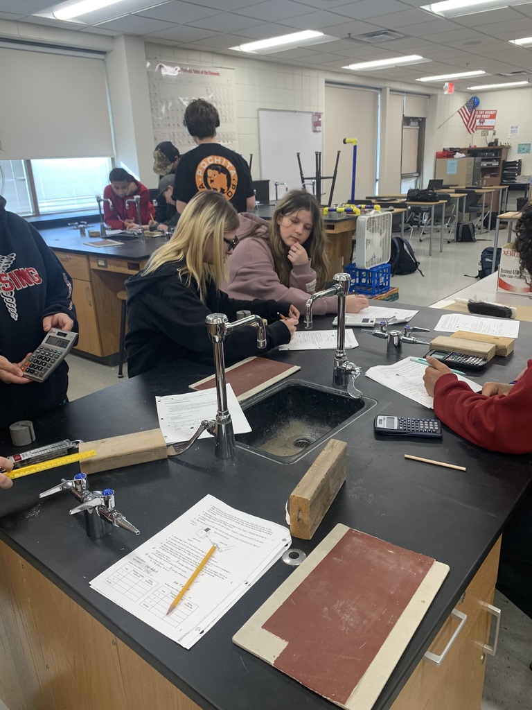multiple students at their tables in science class working on their friction lab