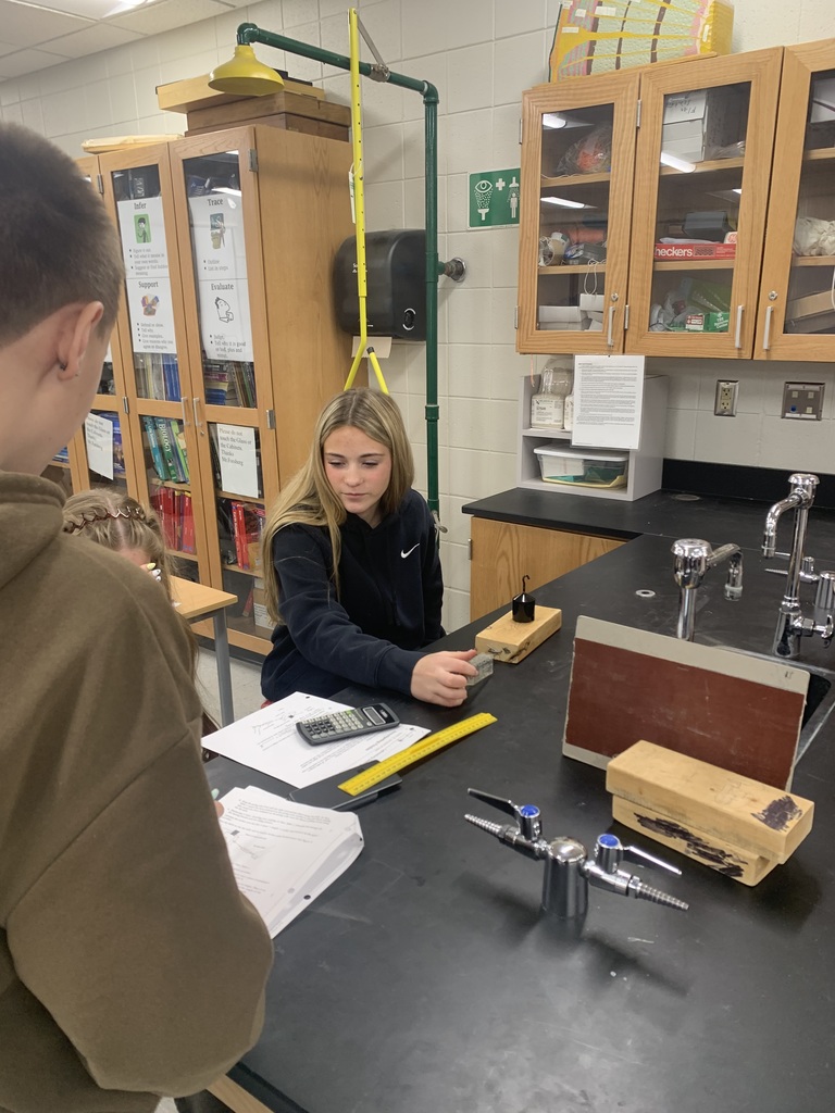 female student pulling a block of wood for their lab in science