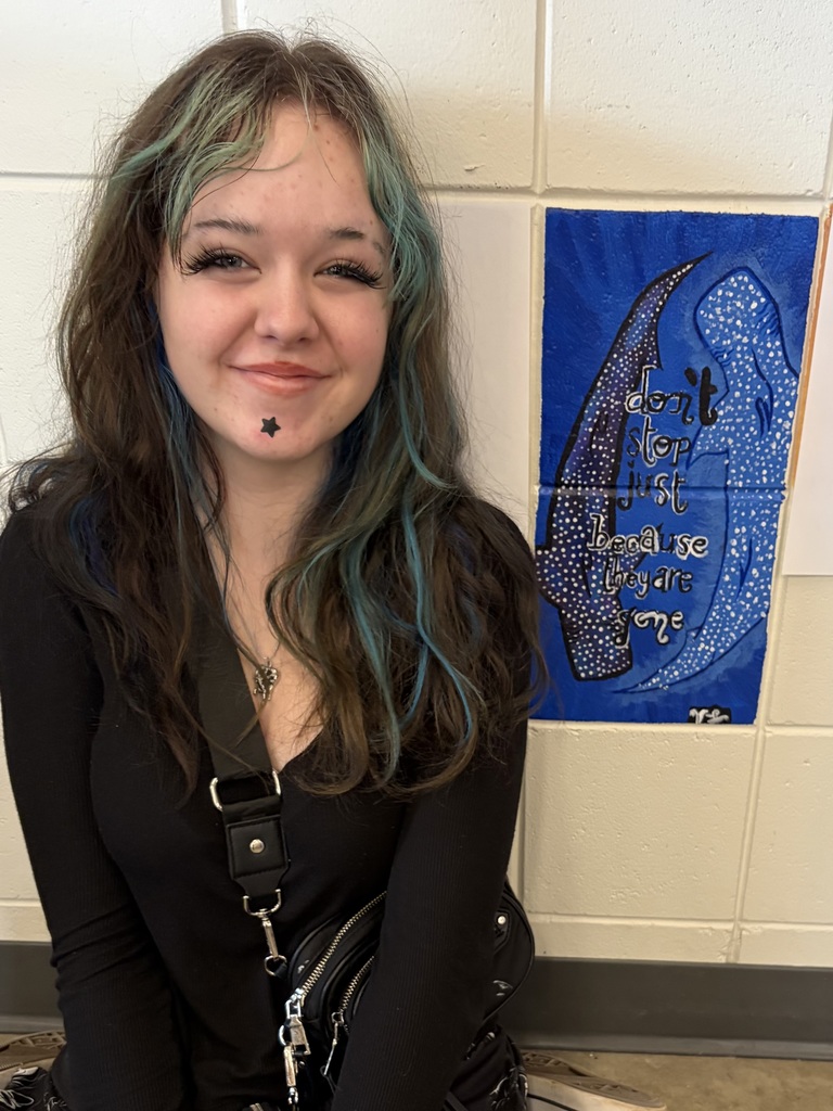 female artist of the week next to the two bricks she painted saying "don't just stop because they are done" 