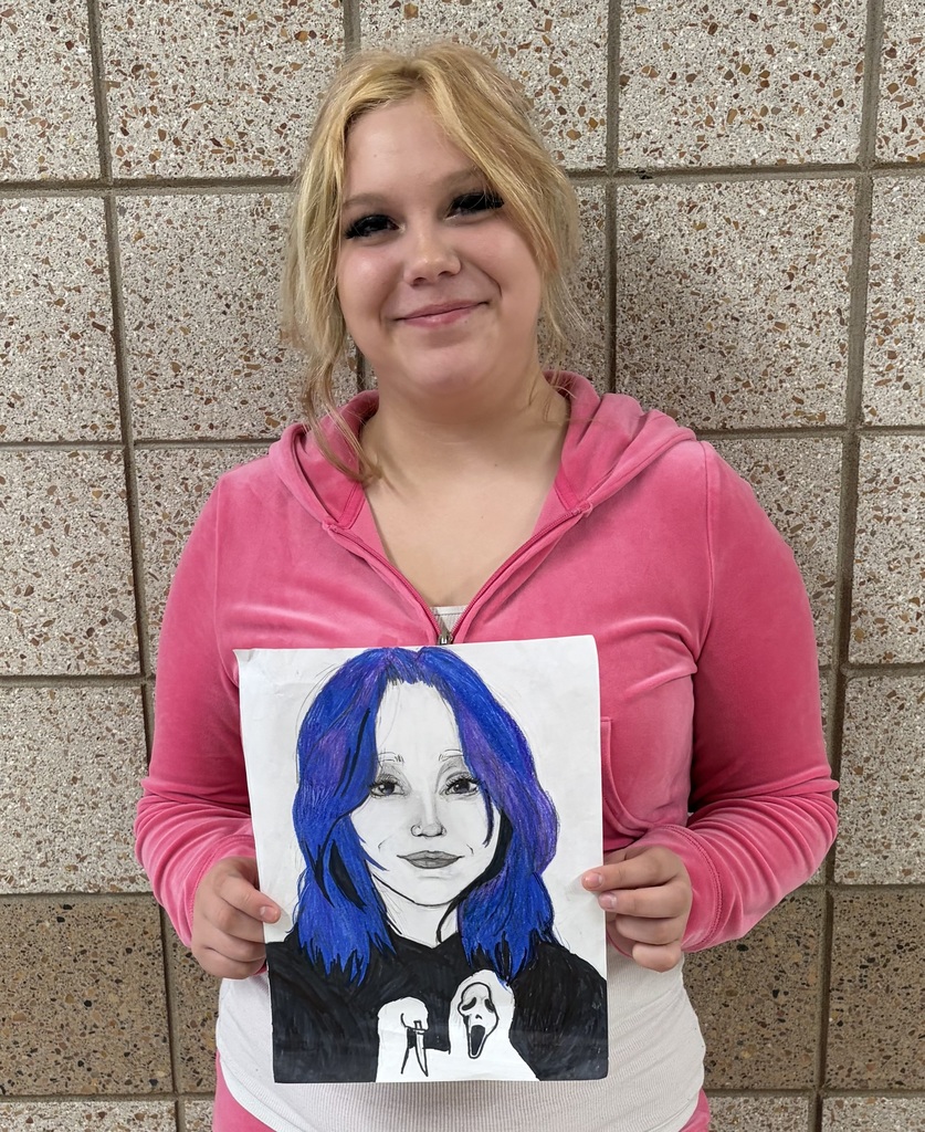female student holding a self portrait drawing of herself with blue hair