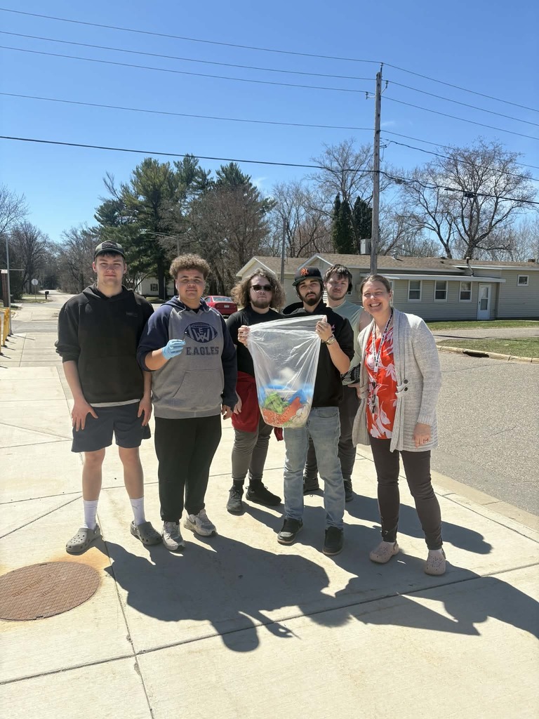 students and a teacher with their bag of trash that they collected