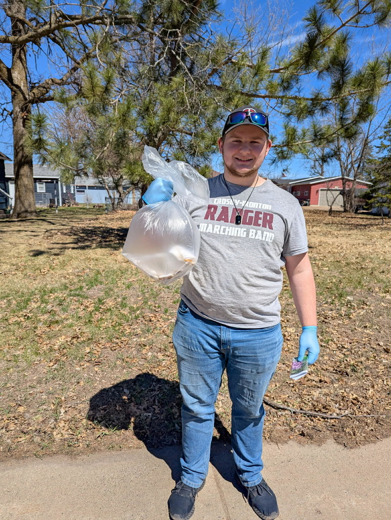 a male student holding up his trash bag that he collected