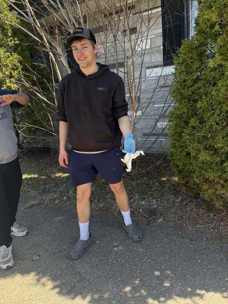 male student picking up garbage from a yard