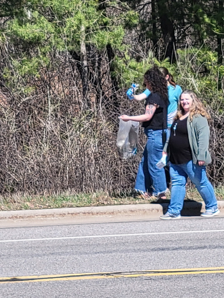 two staff members and a student walking along the road picking up trash