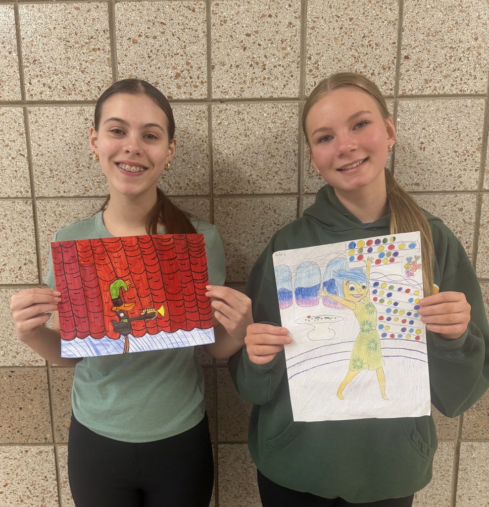 two female 8th graders holding a drawing of daffy duck and Joy from Inside Out