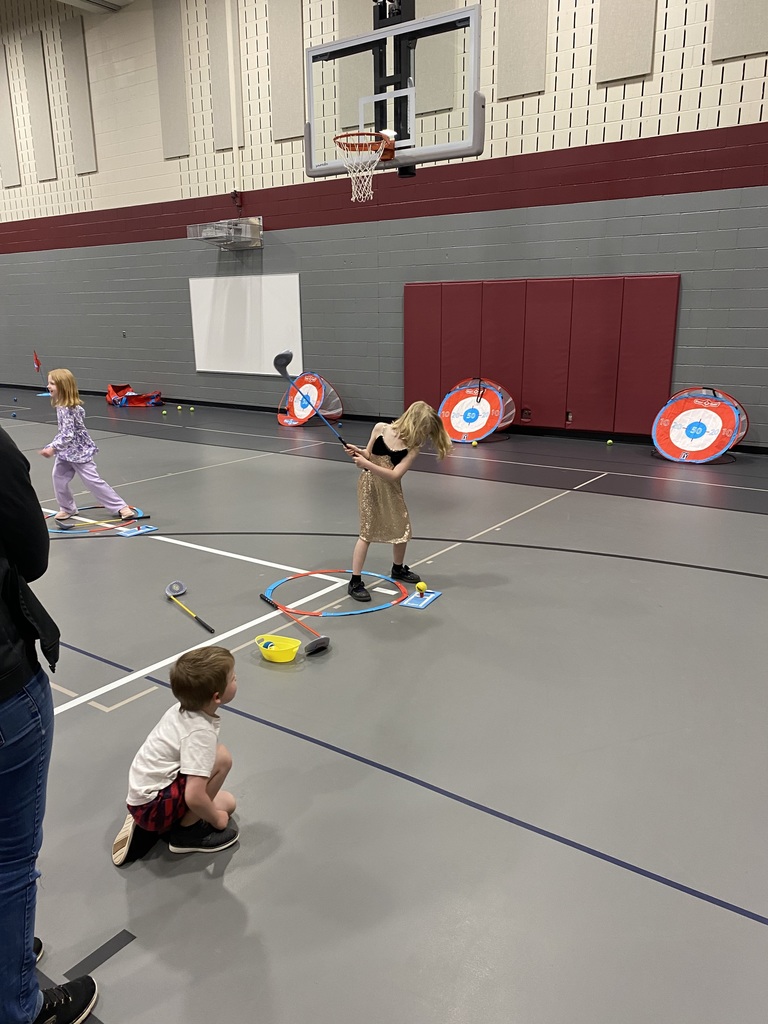 1st grade female taking a swing at the golf ball at her expo